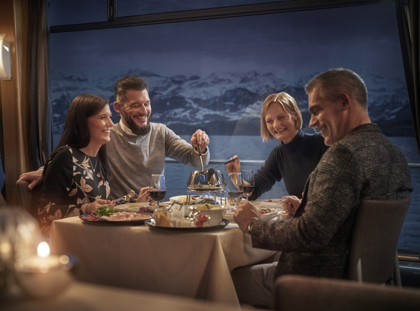 Gruppe von Freunden isst gemeinsam Fondue Chinoise auf dem Schiff. 
