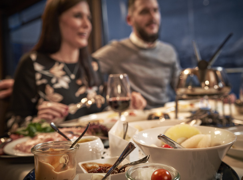 Zwei Personen sitzen an einem Tisch und geniessen ein Fondue Chinoise auf dem Schiff.