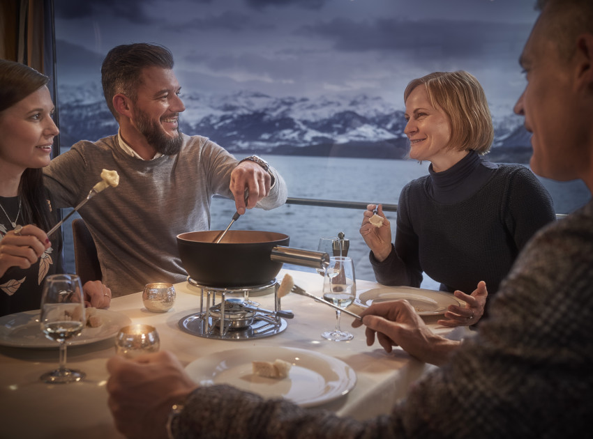 Gruppe von Freunden isst Fondue auf dem Schiff