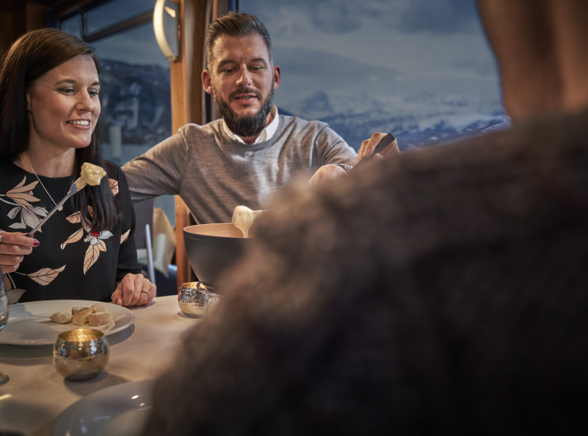 Pärchen beim Fondue Essen auf dem Schiff mit Bergen im Hintergrund