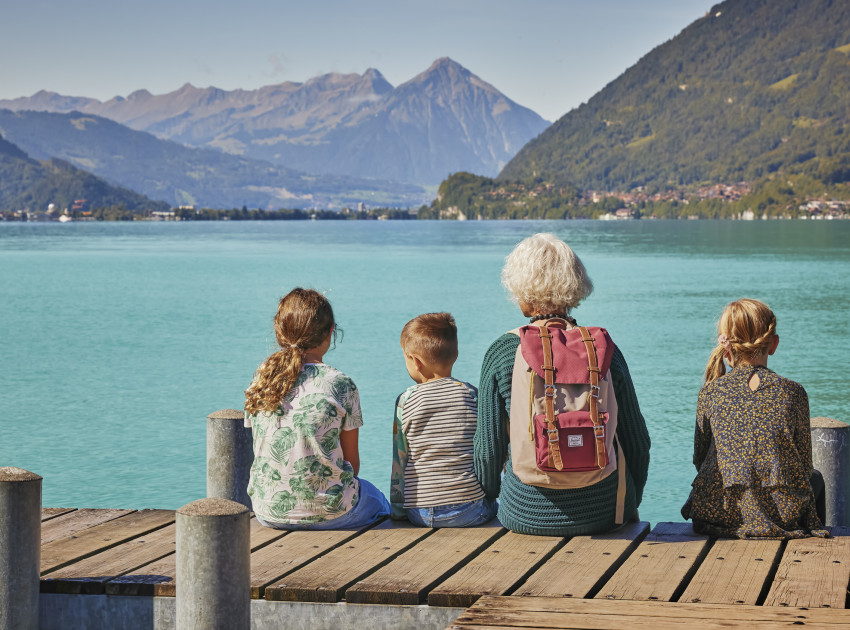 Grossmutter mit Grosskindern auf dem Steg in Iseltwald mit Blick auf Brienzersee und Berge