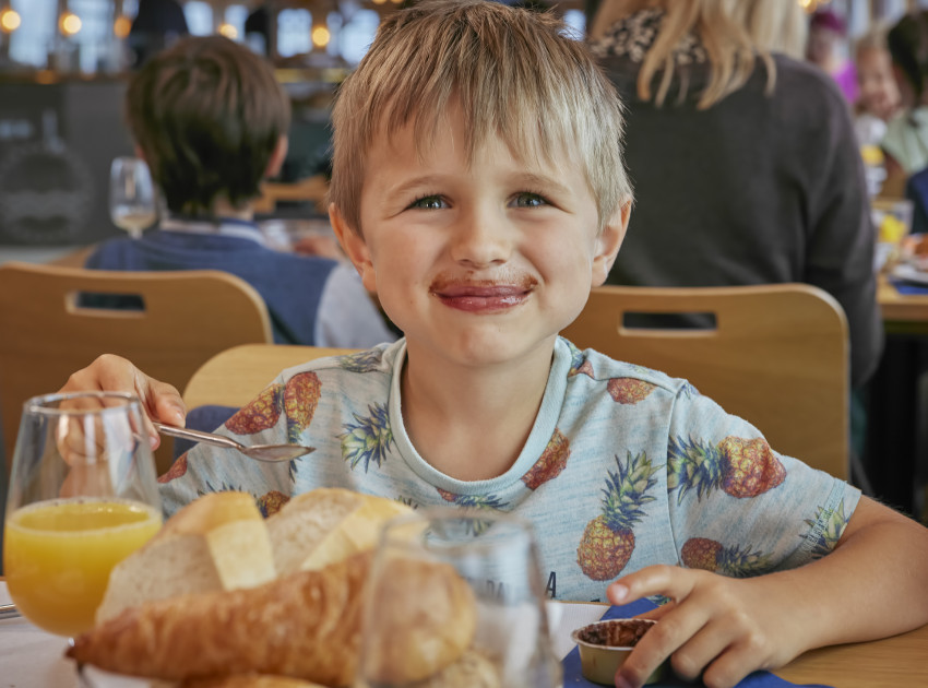 Kleiner Junge am Tisch mit Nutella-Mund