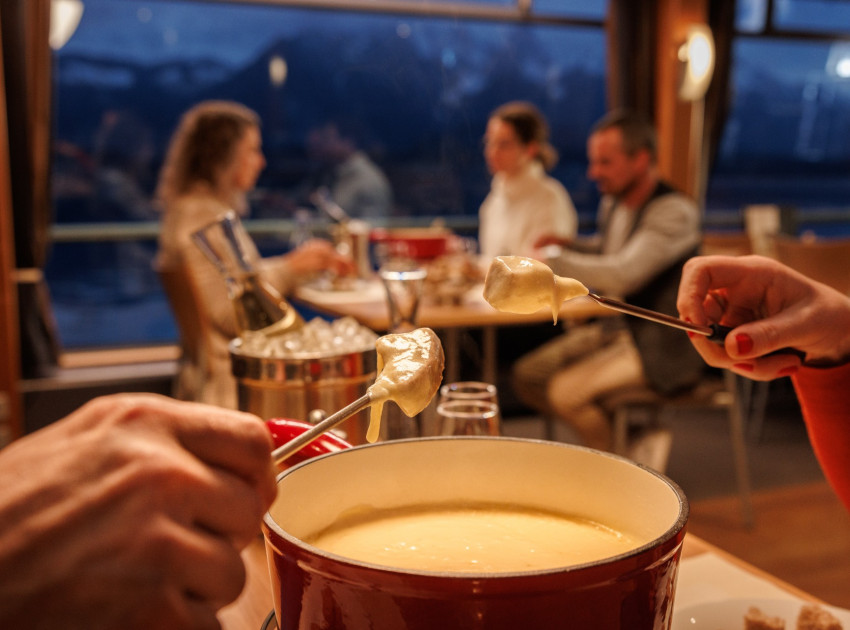 Käsefondue auf dem Schiff mit Personen an Fensterplatz im Hintergrund