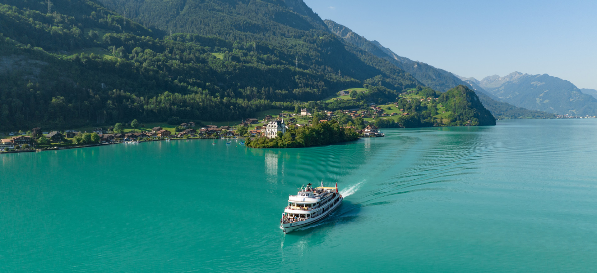 MS Brienz auf türkisfarbenem Brienzersee mit Iseltwald und Inseli im Hintergrund