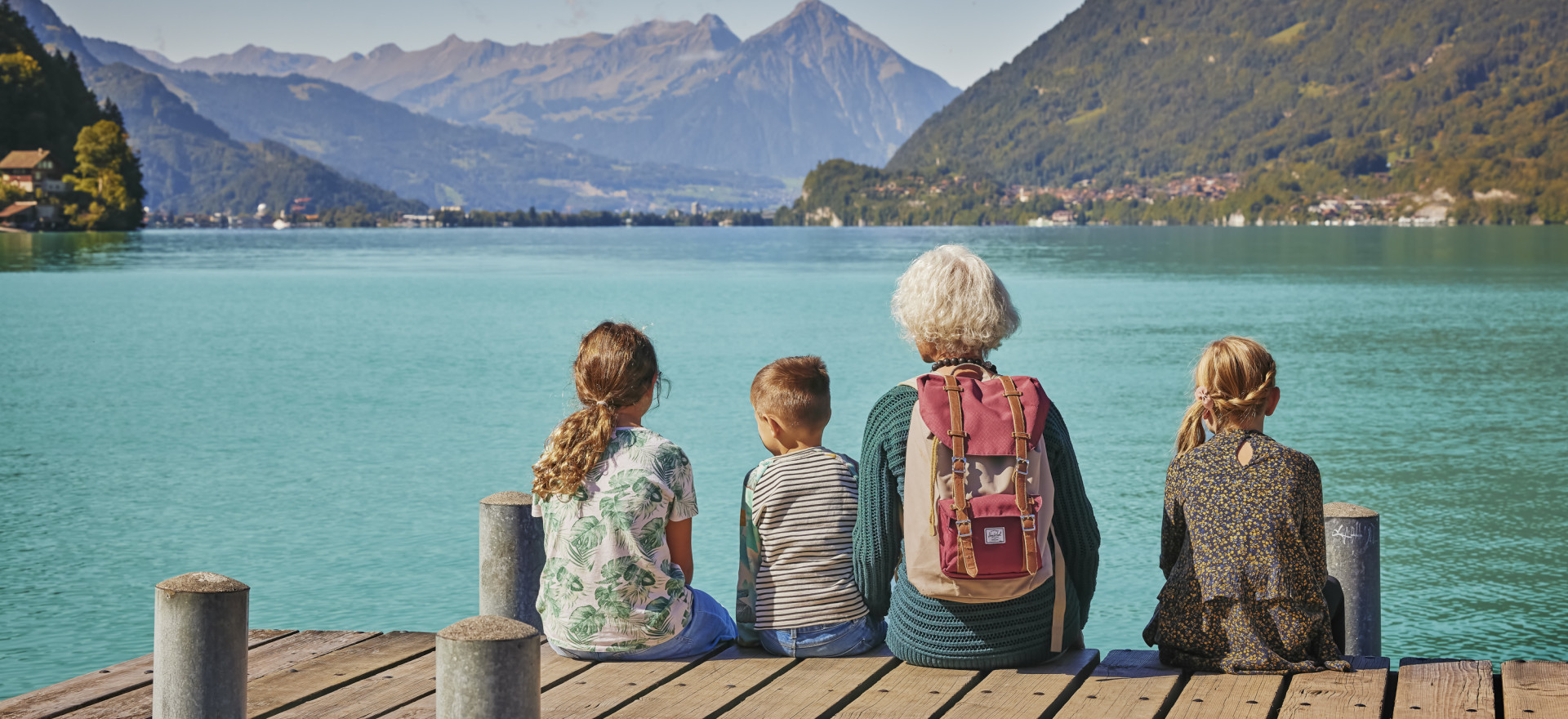 Grossmutter mit Grosskindern auf dem Steg in Iseltwald mit Blick auf Brienzersee und Berge