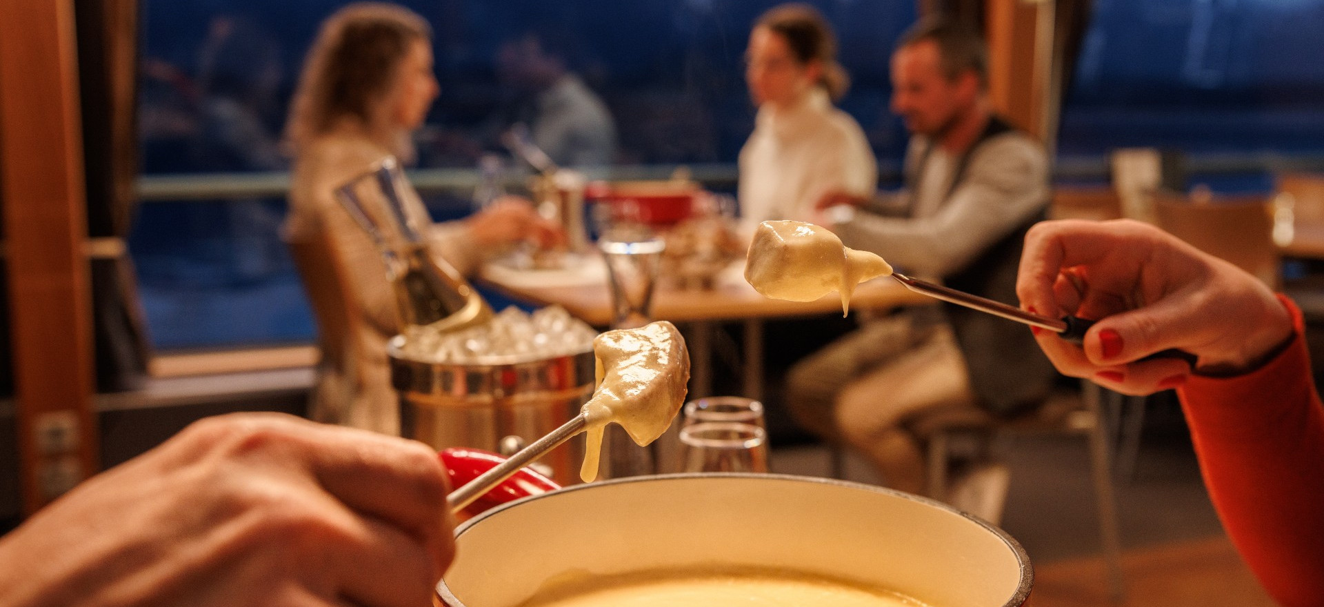 Käsefondue auf dem Schiff mit Personen an Fensterplatz im Hintergrund