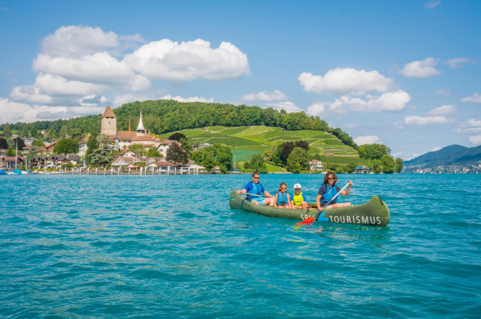 See mit Kanu im Vodergrund und Bucht mit Rebbergen im Hintergrund