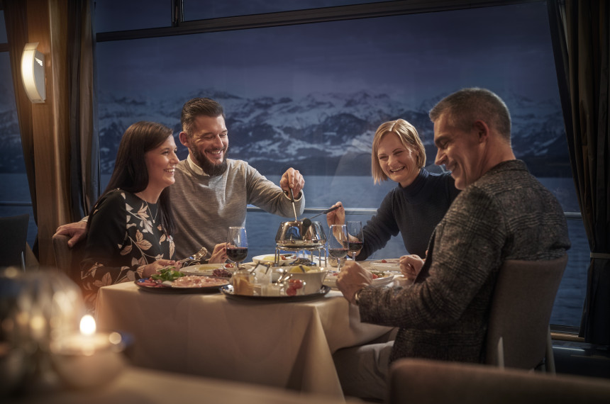 Gruppe von Freunden isst gemeinsam Fondue Chinoise auf dem Schiff. 