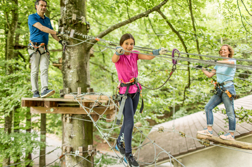 Kinder auf Seilen balancierend zwischen Bäumen