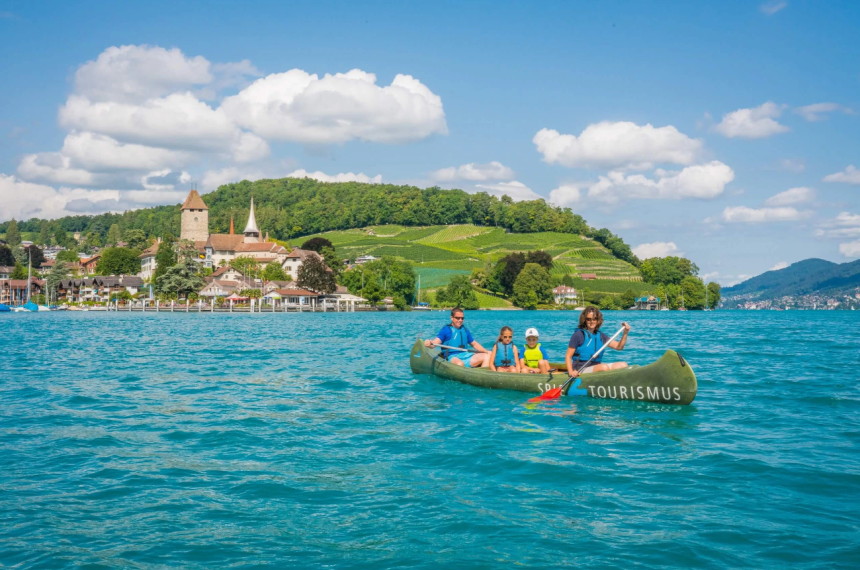 See mit Kanu im Vodergrund und Bucht mit Rebbergen im Hintergrund